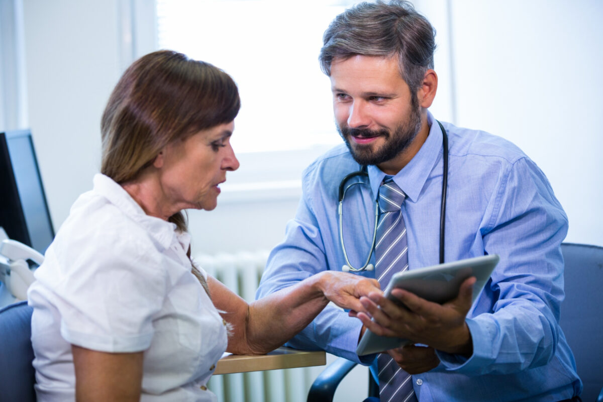 Doctor engaging with patient over digital tablet.