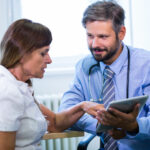 Doctor engaging with patient over digital tablet.