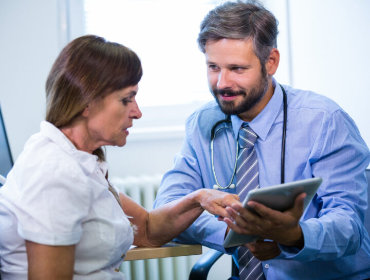 Doctor engaging with patient over digital tablet.