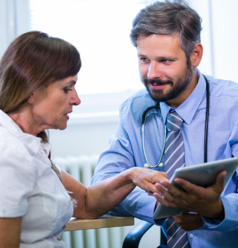 Doctor engaging with patient over digital tablet.